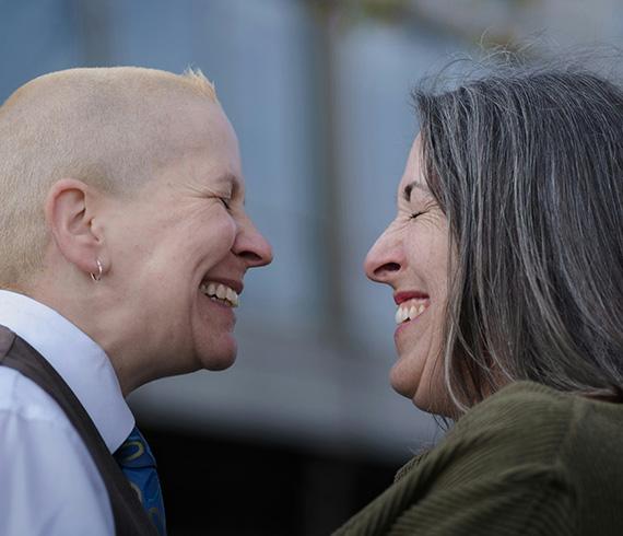 Zwei zugewandte Menschen, die sich mit geschlossenen Augen anlachen