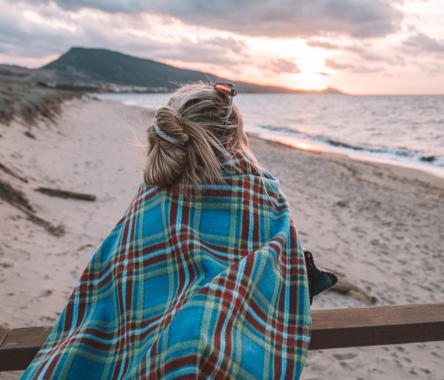 Frau betrachtet Sonnenuntergang am Meer