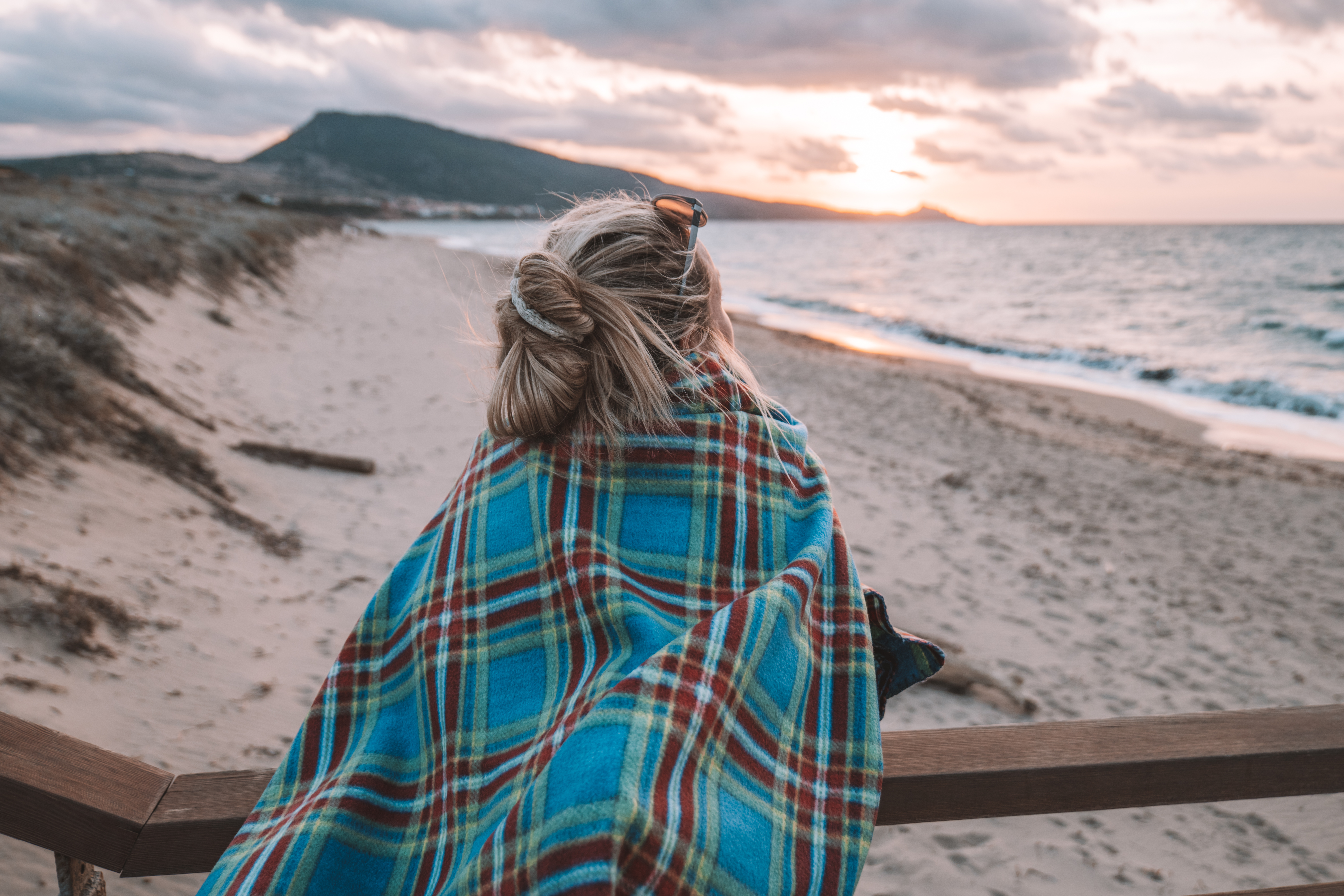 Frau betrachtet Sonnenuntergang am Meer